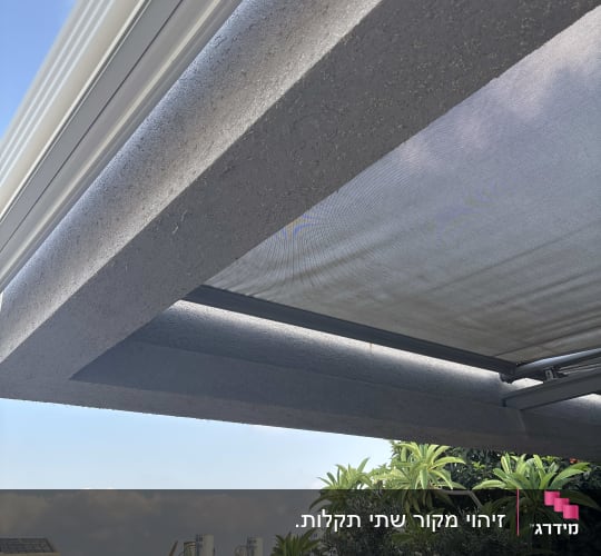סוכך מותקן מעל גינה עם נוף עירוני